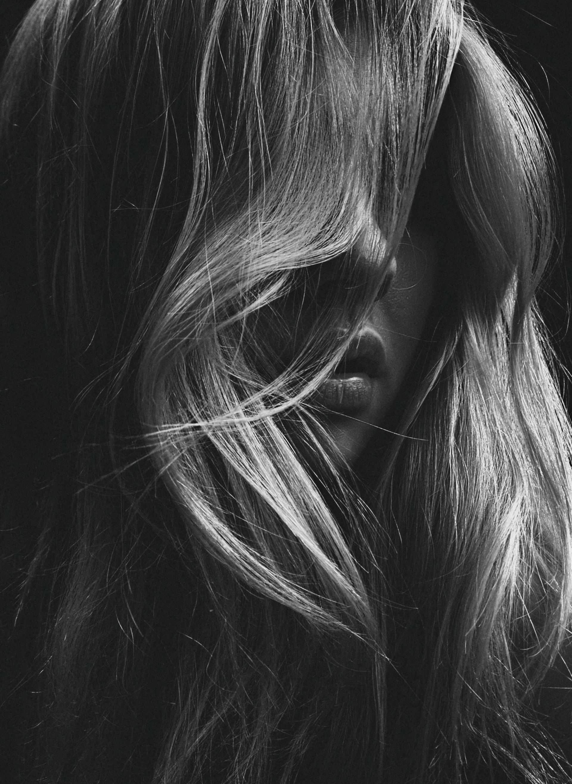 Long hair covering face in dramatic black and white photograph.