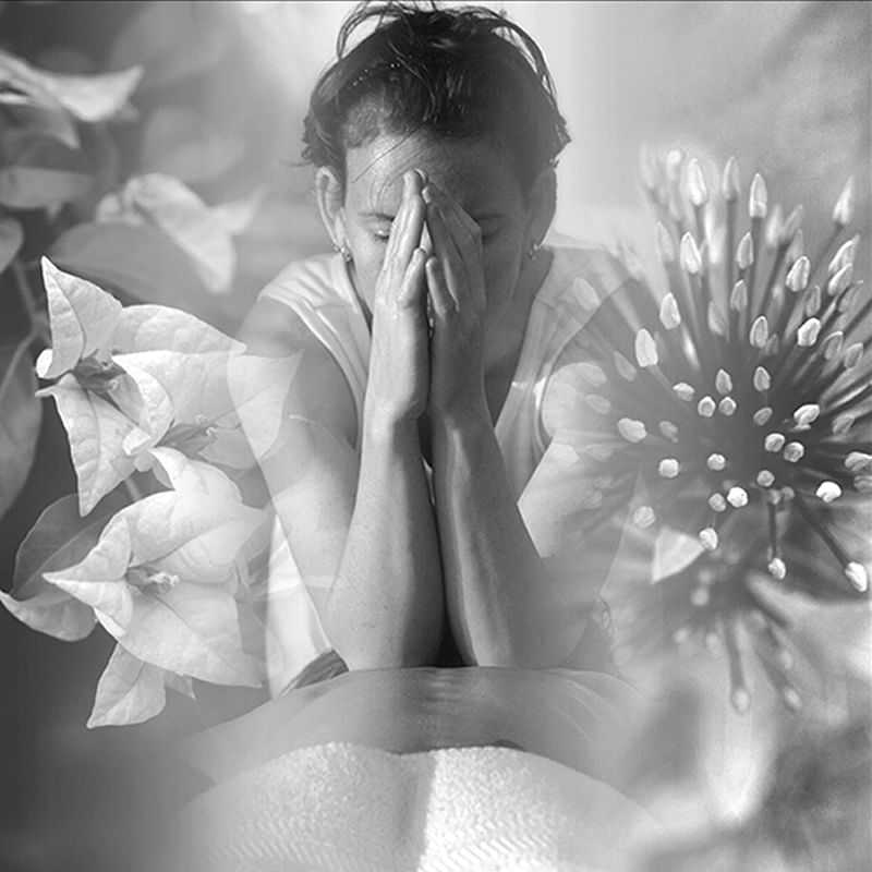 A person with hands covering face amidst floral overlays, reflecting contemplation.