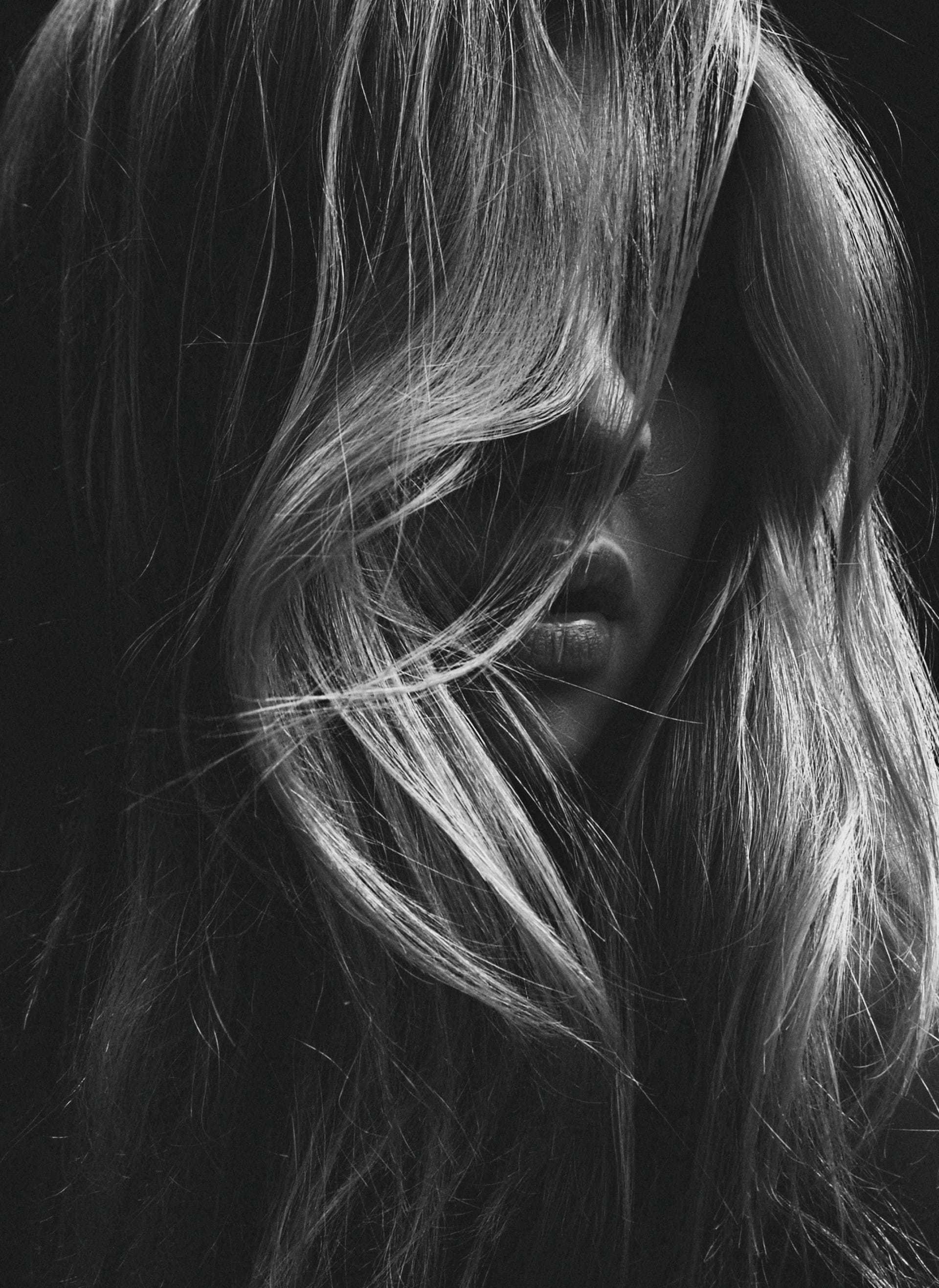 Long hair covering face in dramatic black and white photograph.