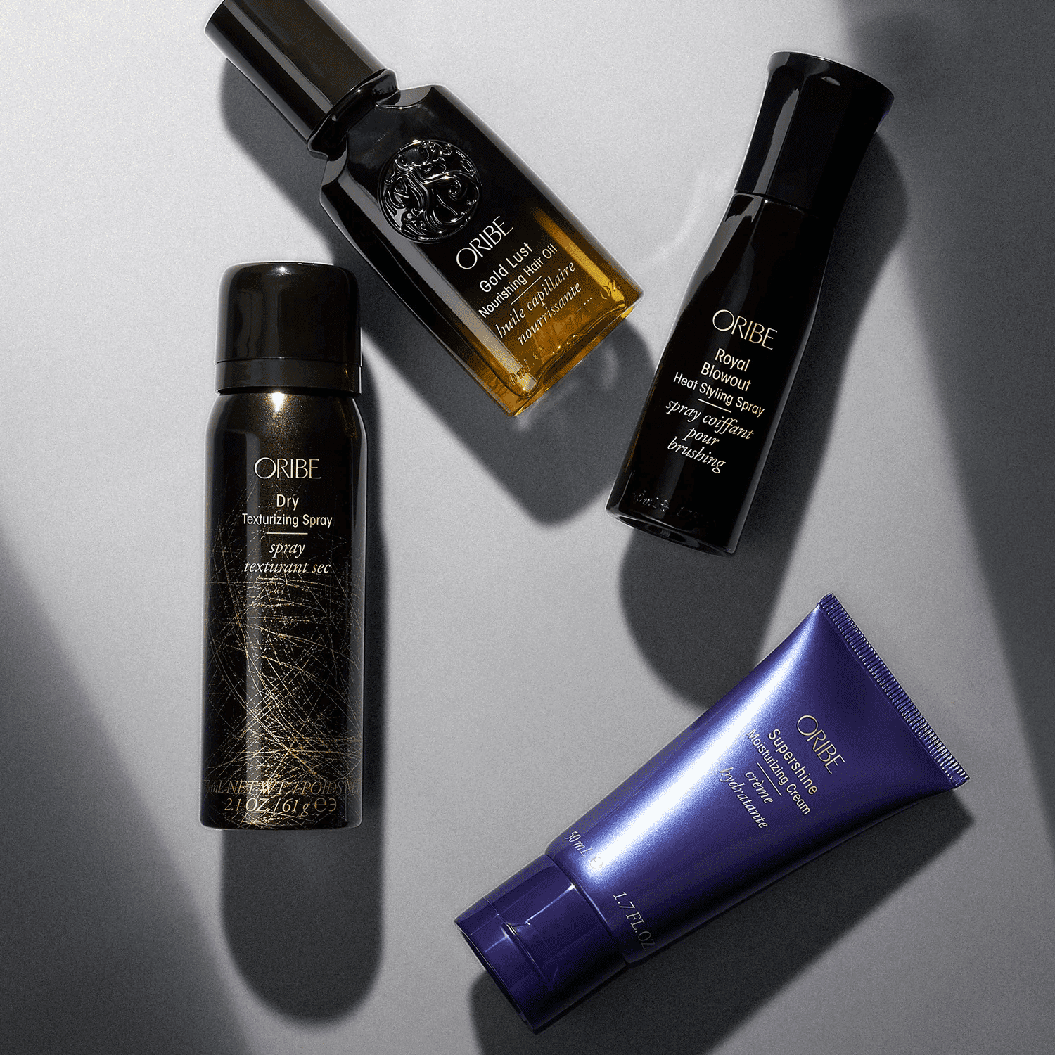 Four Oribe hair products arranged on a gray background.